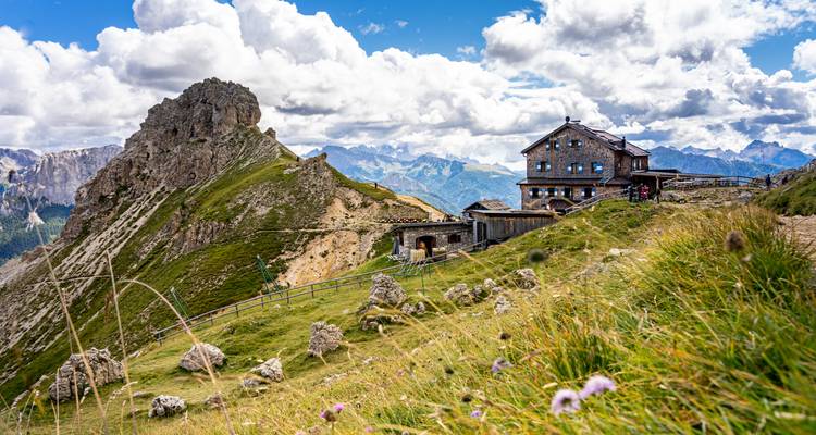 Refugio de montaña en una ladera rocosa con vistas panorámicas.