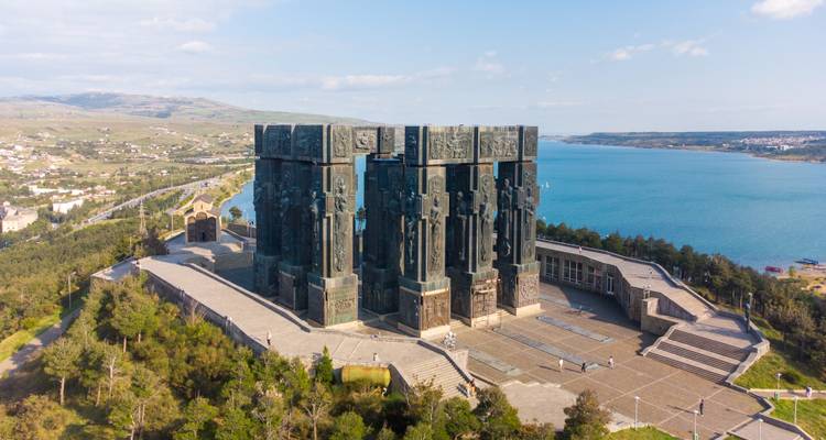 Monument met grote sculpturen bij een meer.