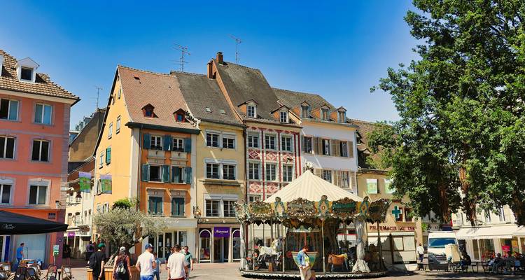 Bunte Gebäude, die einen Platz mit einem Karussell umgeben.