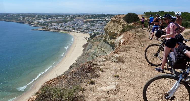 Cyclistes sur une falaise surplombant une plage et un océan.