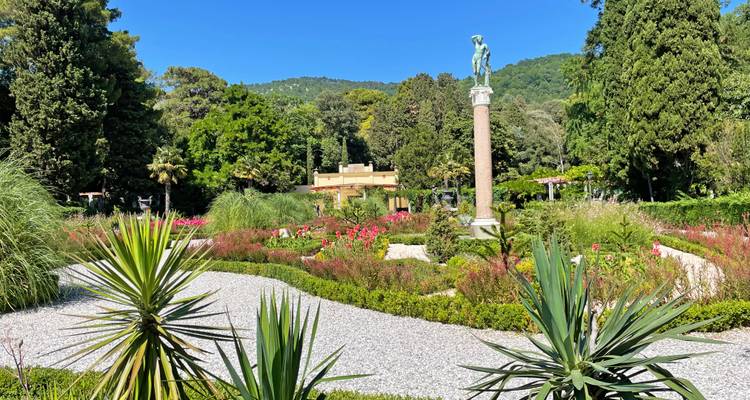 Ein gestalteter Garten mit einer Statue auf einer Säule und Steinwegen.