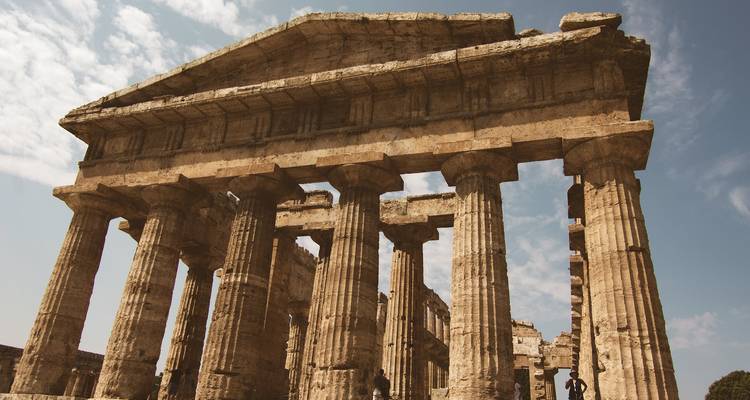 Oude ruïnes met grote stenen zuilen tegen een heldere hemel.