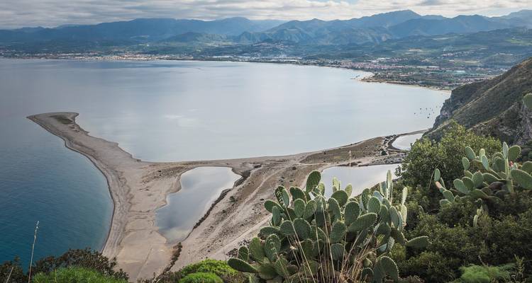 Bovenaanzicht van een kustlijn met een bergachtige achtergrond.