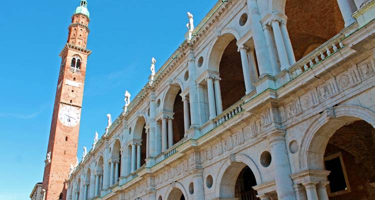 Palladian Basilica with grand white arches and adjacent brick bell tower against clear sky.