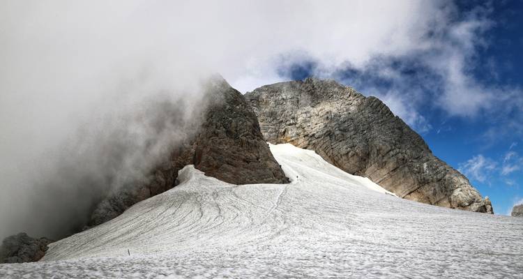 Une montagne enneigée avec un sentier qui monte le long de la pente.