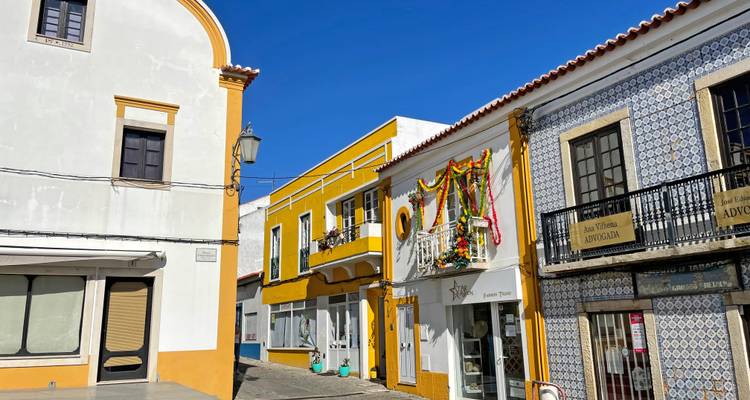 Charmante schmale Straße mit weiß und gelb azulejo-verzierten Gebäuden unter einem leuchtend blauen Himmel.