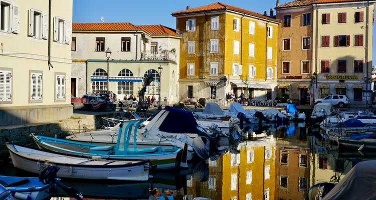 Hafen mit Booten und bunten Gebäuden, die sich im Wasser spiegeln.