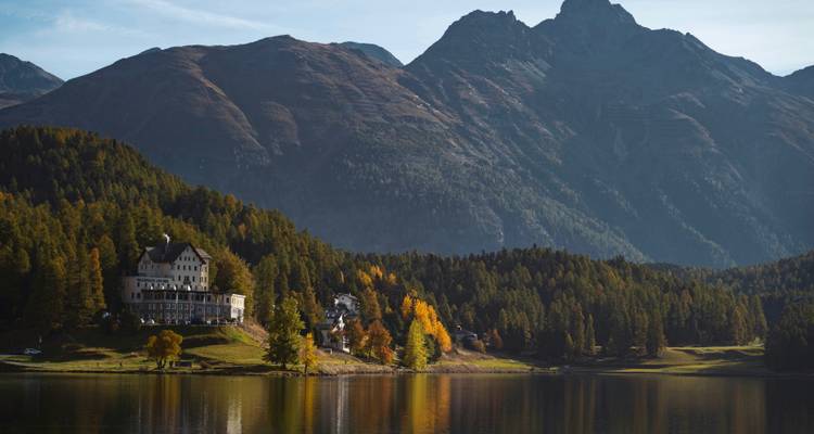 Vue au bord du lac avec un manoir et un arrière-plan montagneux.