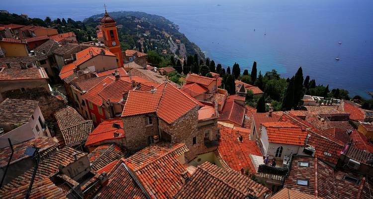 Rooftop view of a town with the sea in the background.