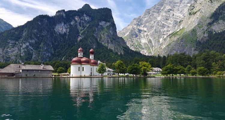 Picturesque church and surrounding Alps reflected in a lake.
