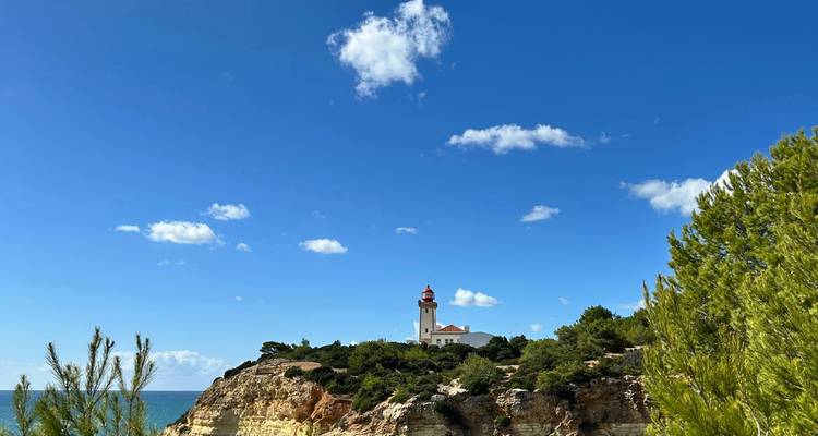 Un phare au sommet d'une falaise avec un ciel bleu clair.