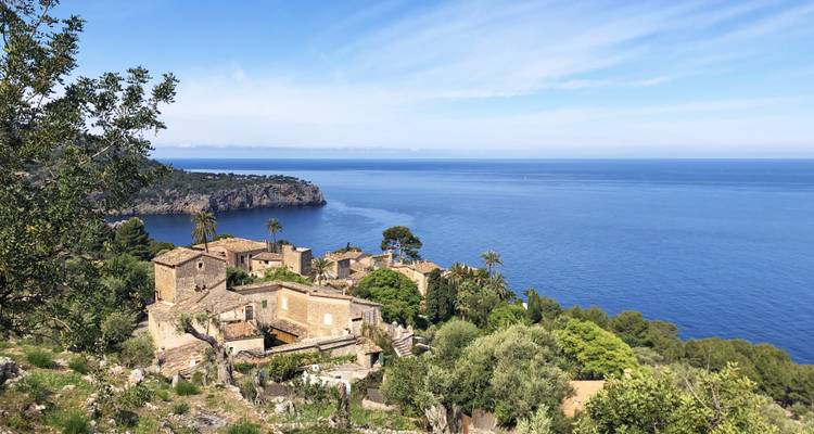 Steindorf auf einer Klippe über dem tiefblauen Mittelmeer mit entferntem Kap.