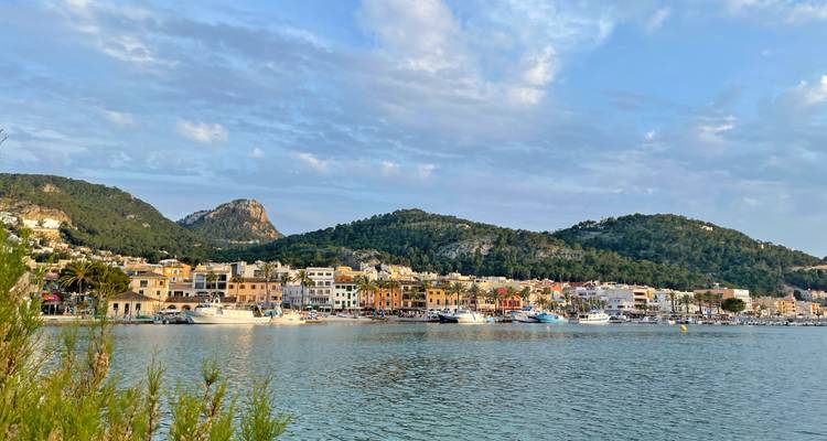 Hafenstadt mit bunten Gebäuden und Booten, die sich im ruhigen Abendwasser spiegeln.