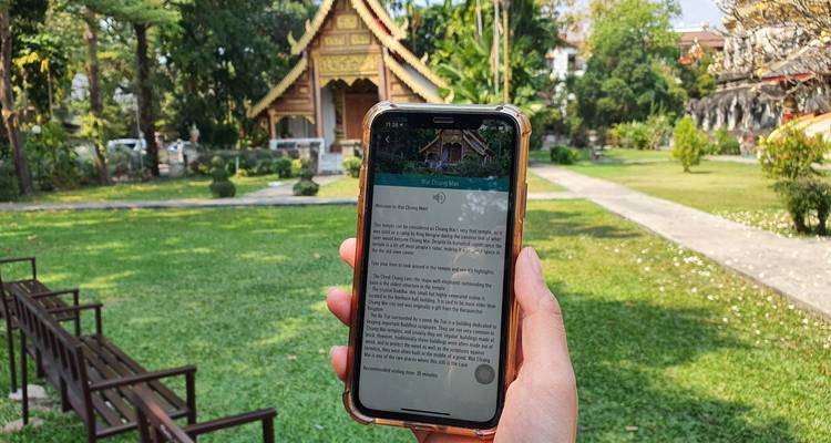 Person, die ein Telefon hält, mit Tempel im Hintergrund.