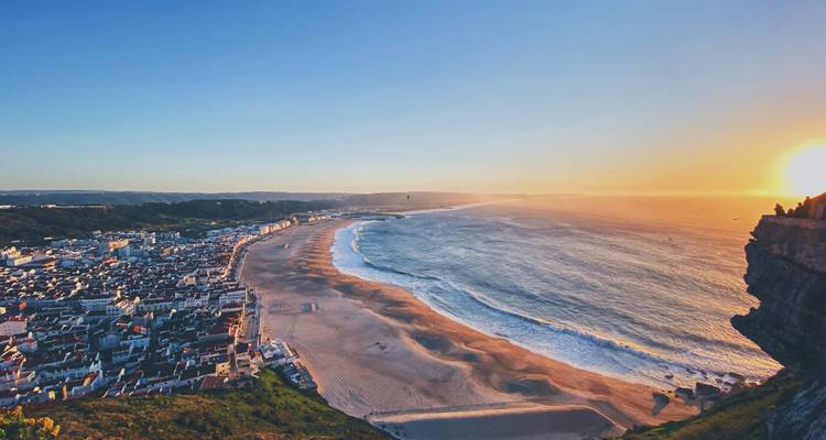 Coastal town with a wide sandy beach and sunset.