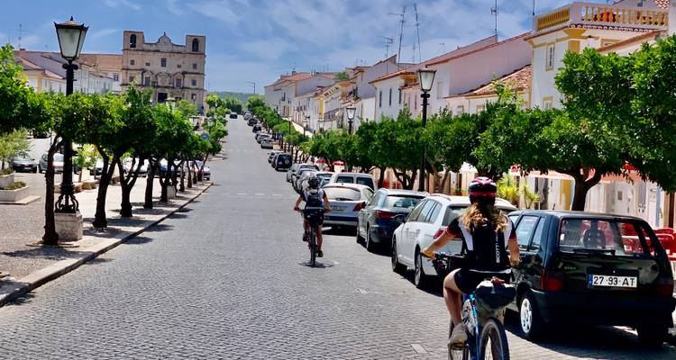 Des cyclistes remontant une rue pavée dans une ville européenne.
