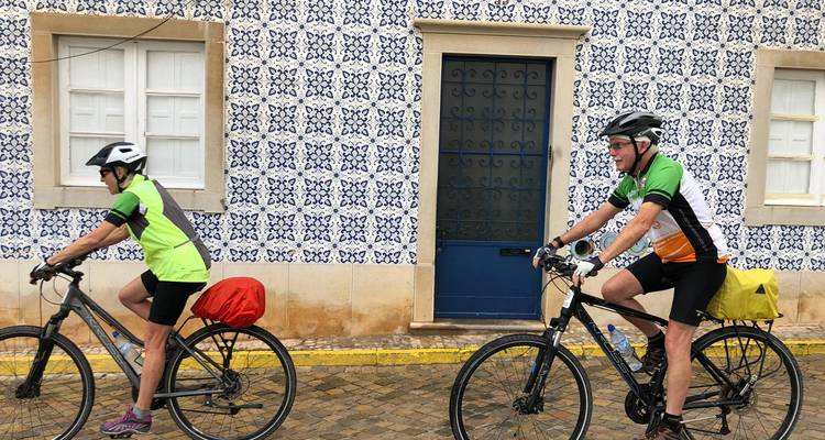 Twee fietsers die voorbij een gebouw met traditionele tegels rijden.
