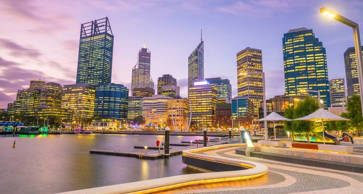 City skyline at dusk with vibrant lights and waterfront.