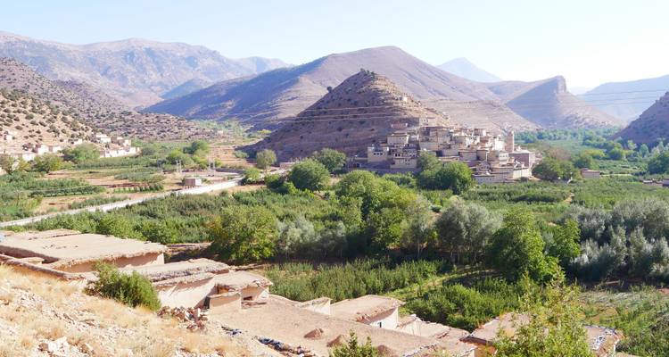 Dorf umgeben von Grün in einem bergigen Tal.