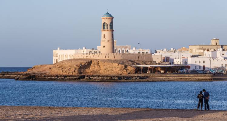 Kusttafereel met een vuurtoren en mensen.