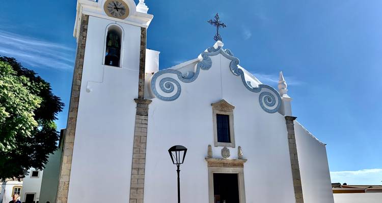 Façade d'église blanche traditionnelle sous un ciel bleu clair.