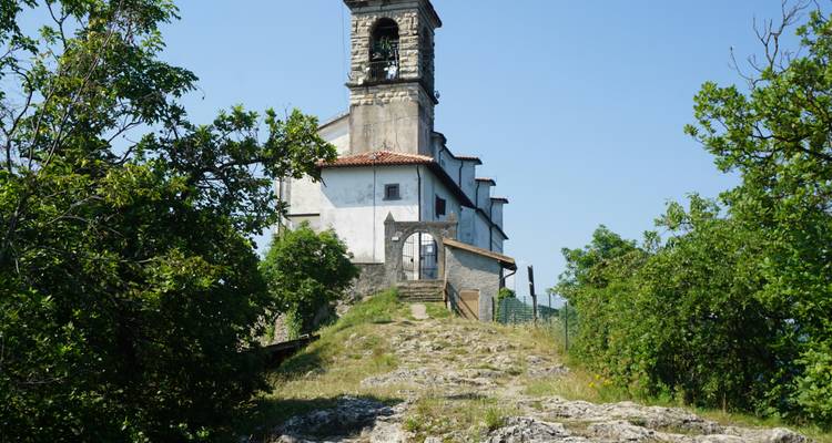 Une église au sommet d'une colline rocheuse entourée d'arbres.