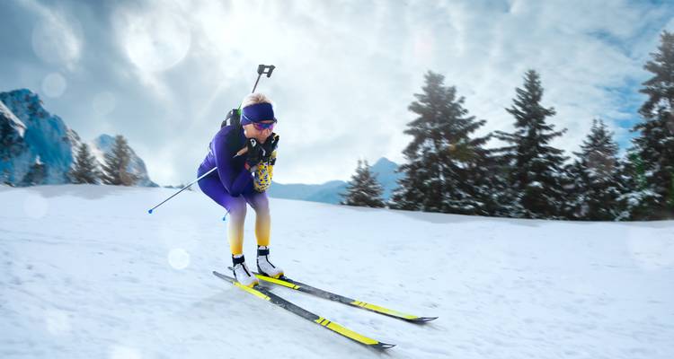 Personne faisant du ski dans un paysage enneigé avec des arbres et des montagnes en arrière-plan.