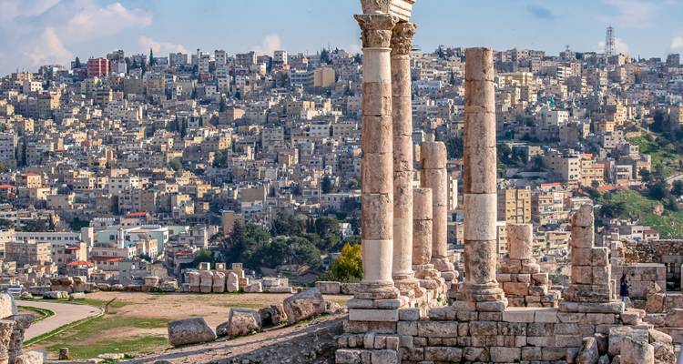 Colonnes romaines antiques avec un paysage urbain d'Amman en arrière-plan.