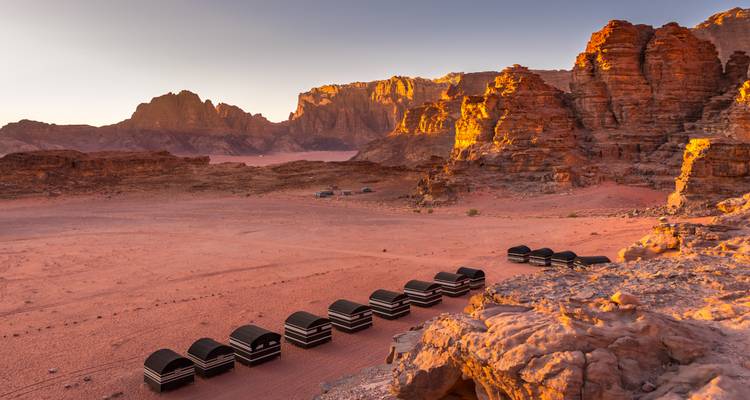 Campement bédouin dans le désert du Wadi Rum avec des formations rocheuses rouges.