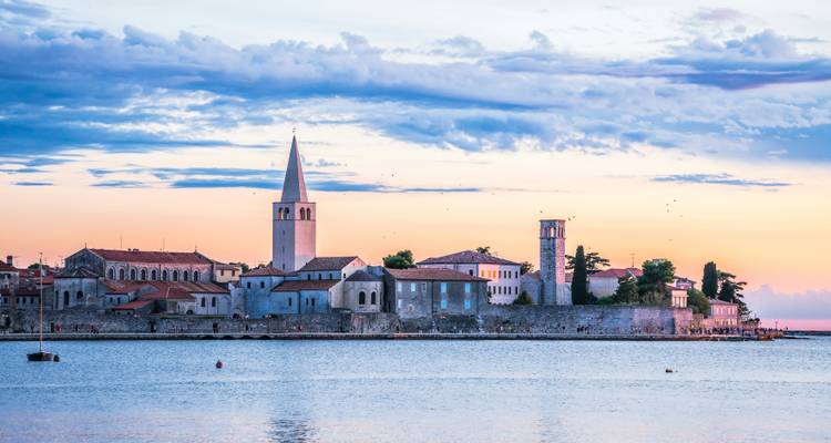 Historic seaside town at sunset with church towers.