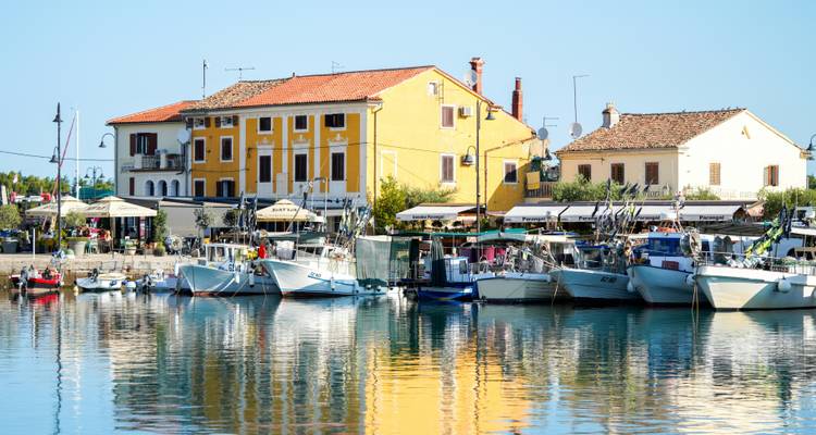 Colorful buildings and boats reflecting in calm water.