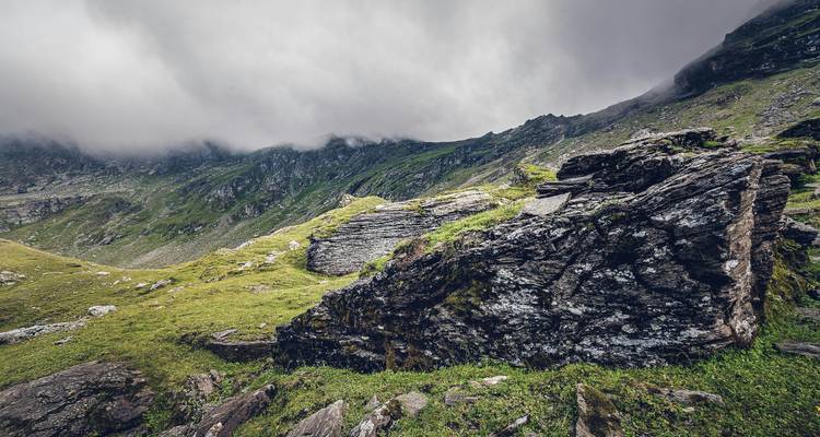 Ciel nuageux au-dessus d'un paysage montagneux accidenté avec un terrain rocheux.