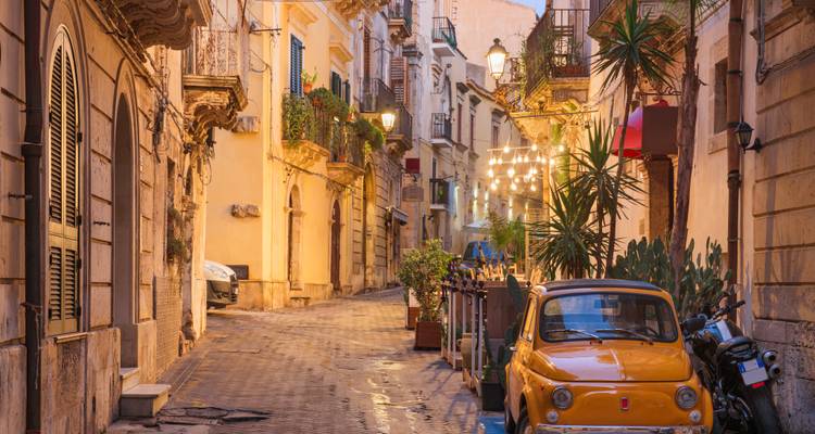 Rue étroite dans une ville historique avec une voiture vintage garée.