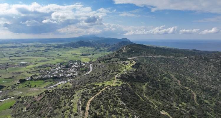 Vue d'un vaste paysage vert avec des montagnes et la mer au loin.