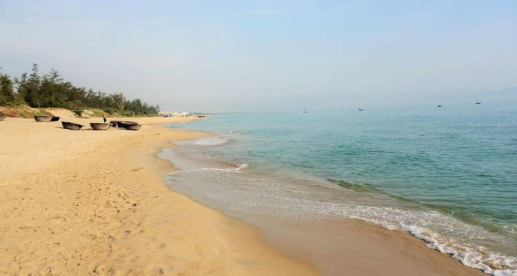 Ruhiger Strand mit goldenem Sand und sanften Wellen.