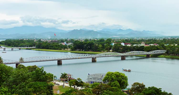 Bridge spanning a tranquil river with hills in the background.