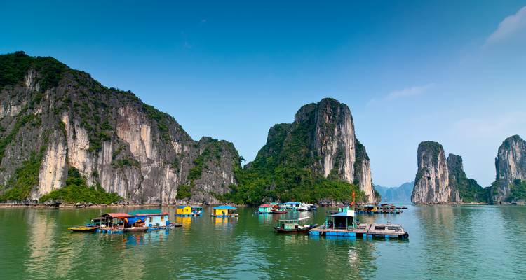Floating fishing village with limestone karsts in the background.