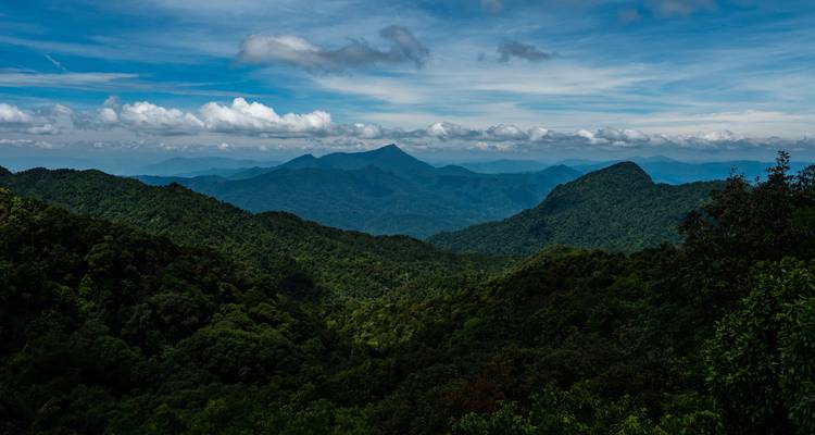 Lush green mountains with a cloudy sky above.