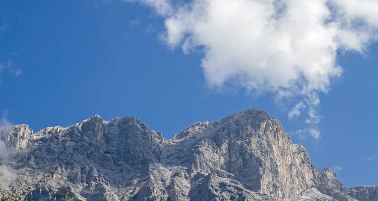 Bergtop tegen een heldere blauwe lucht met wolken.