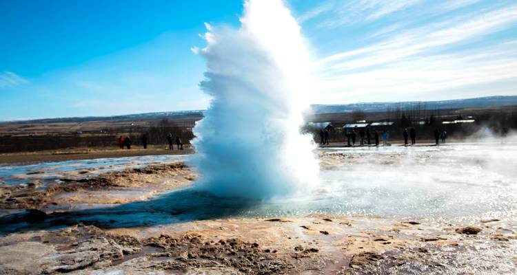 Aktiver Geysir beim Ausbruch, mit Menschen, die aus der Entfernung beobachten.