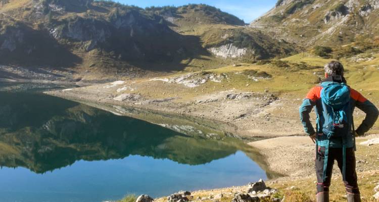 Personne debout devant un lac de montagne.