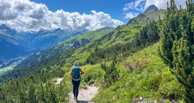 Randonneur marchant le long d'un sentier avec vues panoramiques sur les montagnes.