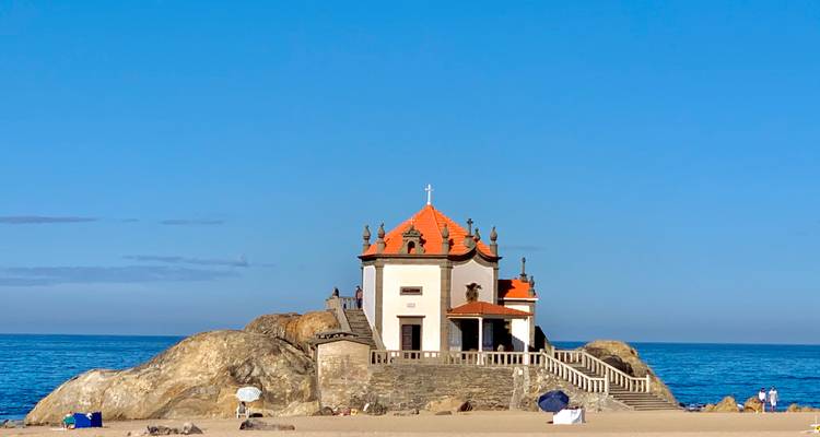 Chapelle sur les rochers au bord de la mer avec ciel bleu.
