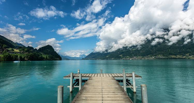 Wooden pier extending into a pristine lake surrounded by mountains.
