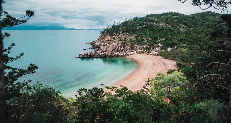 Kleine afgelegen strand omgeven door groene heuvels.