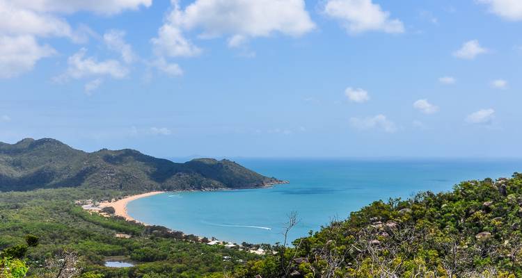 Uitzicht op een strand en baai vanaf een hoog uitkijkpunt.