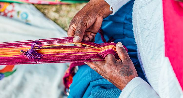A person weaving colorful textiles using traditional methods.