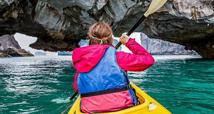 Personne faisant du kayak dans des eaux turquoise avec des falaises rocheuses.