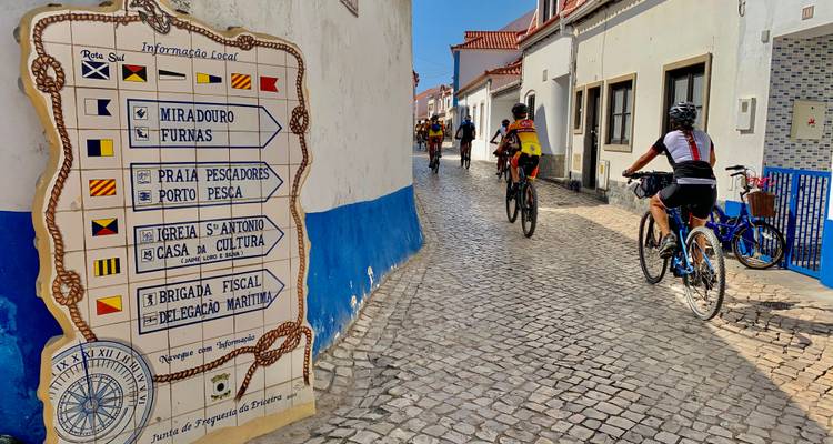 Fietsers die door een geplaveide straat rijden die versierd is met een kleurrijk tegelbord.