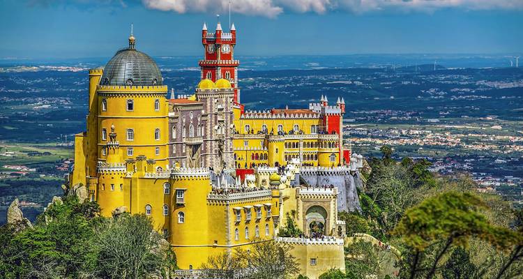 Sierlijk kleurrijk paleis gelegen op een weelderige heuveltop, onder een heldere hemel.